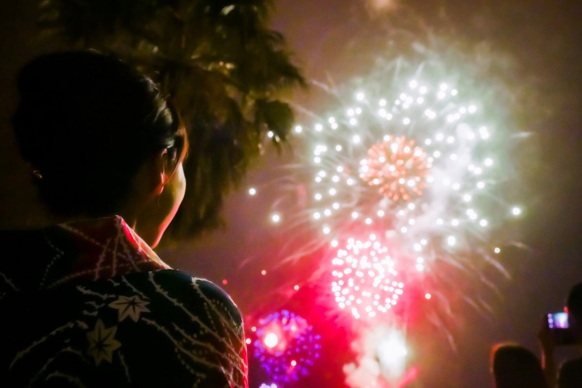 Woman in a yukata watching fireworks at a Japanese summer festival.